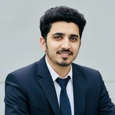 Smiling man in a dark suit and tie against a light background