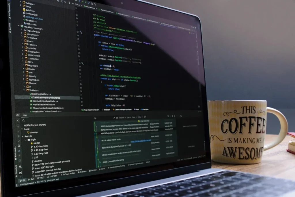 Laptop screen showing a code editor with C# validation code and Git branch history, next to a coffee mug.
